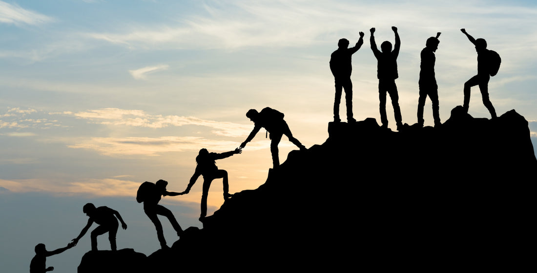 Group of people helping each other climb