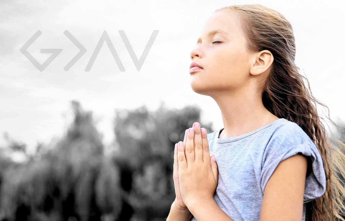 Young girl praying to God outside with G>∧∨ symbol in sky