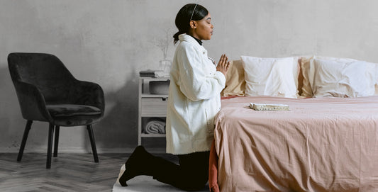 Wife praying beside her bed on her knees